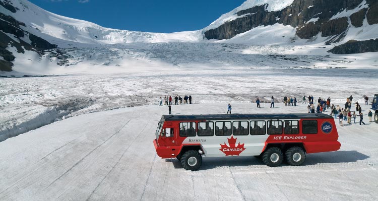 A Glacier Adventure Ice Explorer on the Columbia Icefield with groups of people stand on the icefield.