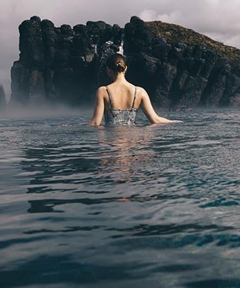 A person in a pool walking towards a rock feature.