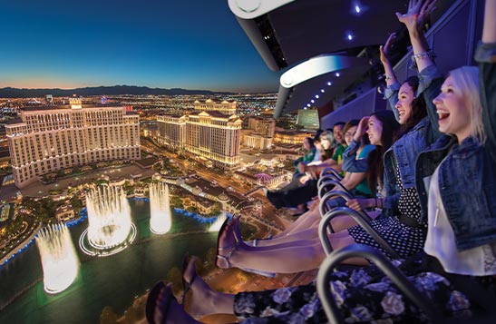 A group of people on a flight ride, superimposed over the Las Vegas Strip