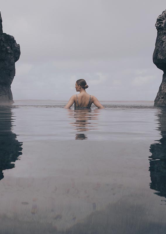A person in a pool between two tall rock features.
