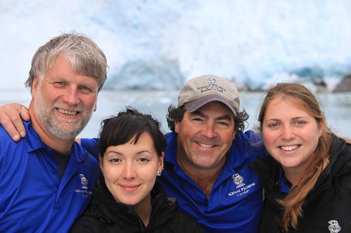 Four Kenai Fjords Tours workers smile in front of a glacier