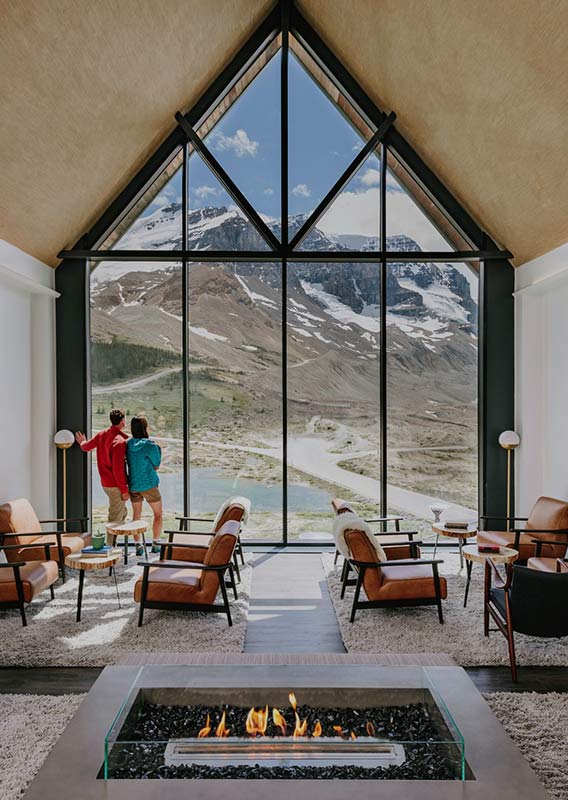 A lounge with a large window view towards mountains and a glacier.
