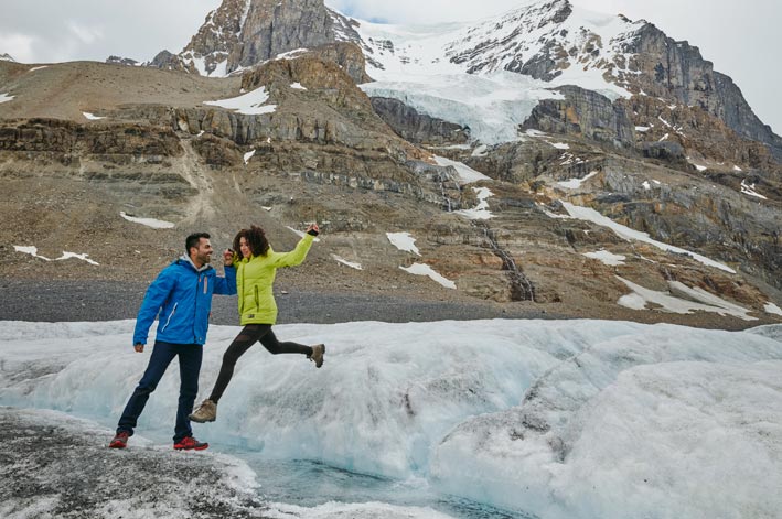 Two people jump from one part of a glacier to another