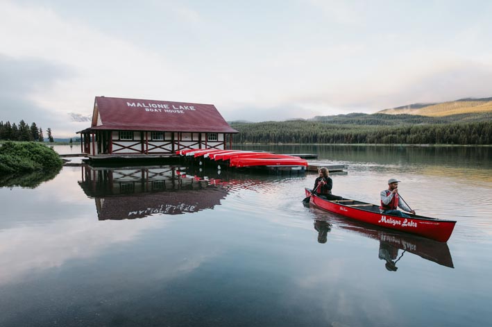 Two canoers paddle away from the Maligne Lake Boat House
