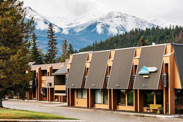 A hotel building in front of forested hillsides and mountains.