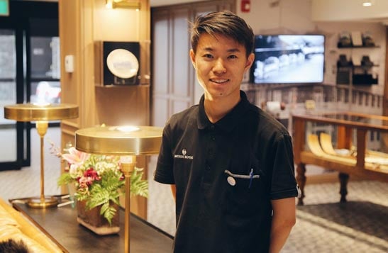 A hotel worker stands in an elegantly decorated lounge.