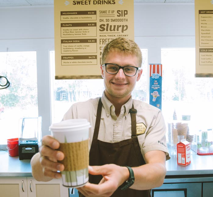 A man serves a cup of coffee in a retro-style cafe.