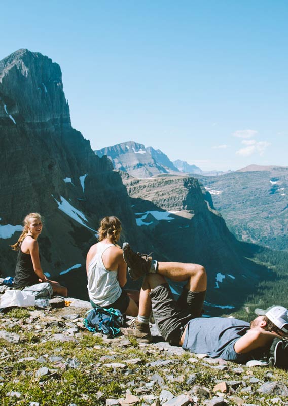 Hikers take a break and sit high above a wide forested valley.