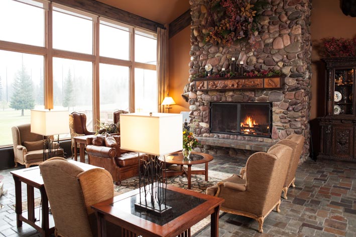 The Grouse Mountain Lodge hotel lounge with stone fireplace and chairs around.