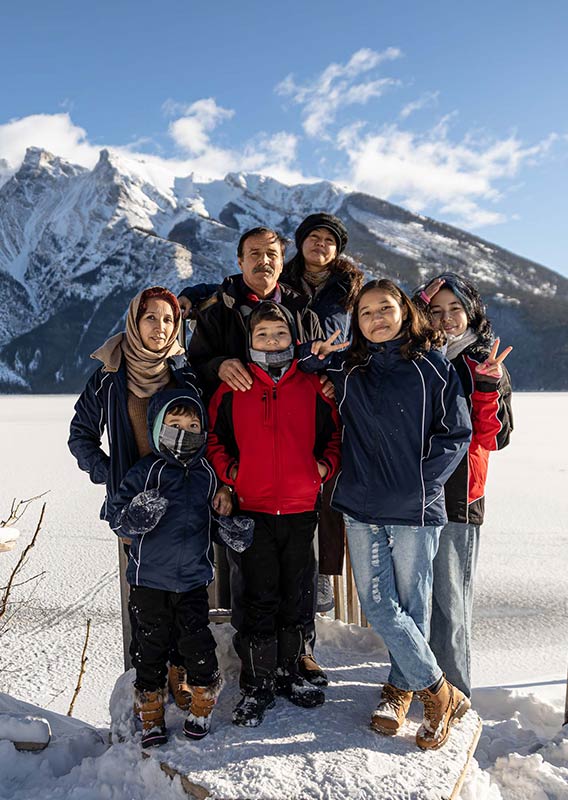 A family poses in front a frozen Lake Minnewanka in winter.