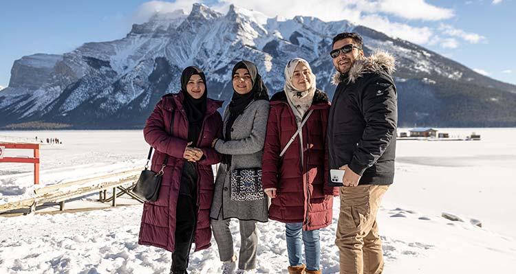 A group of Afghani immigrants pose outside Lake Minnewanka in the winter.